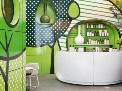 Bright, colourful modern hair salon interior with a curved white reception counter and shelves of plain unlabelled colou