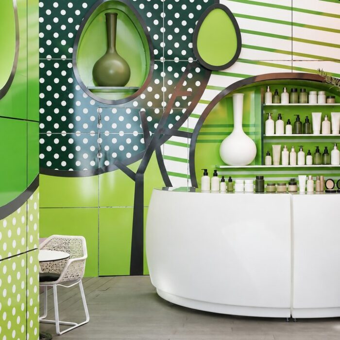 Bright, colourful modern hair salon interior with a curved white reception counter and shelves of plain unlabelled colou