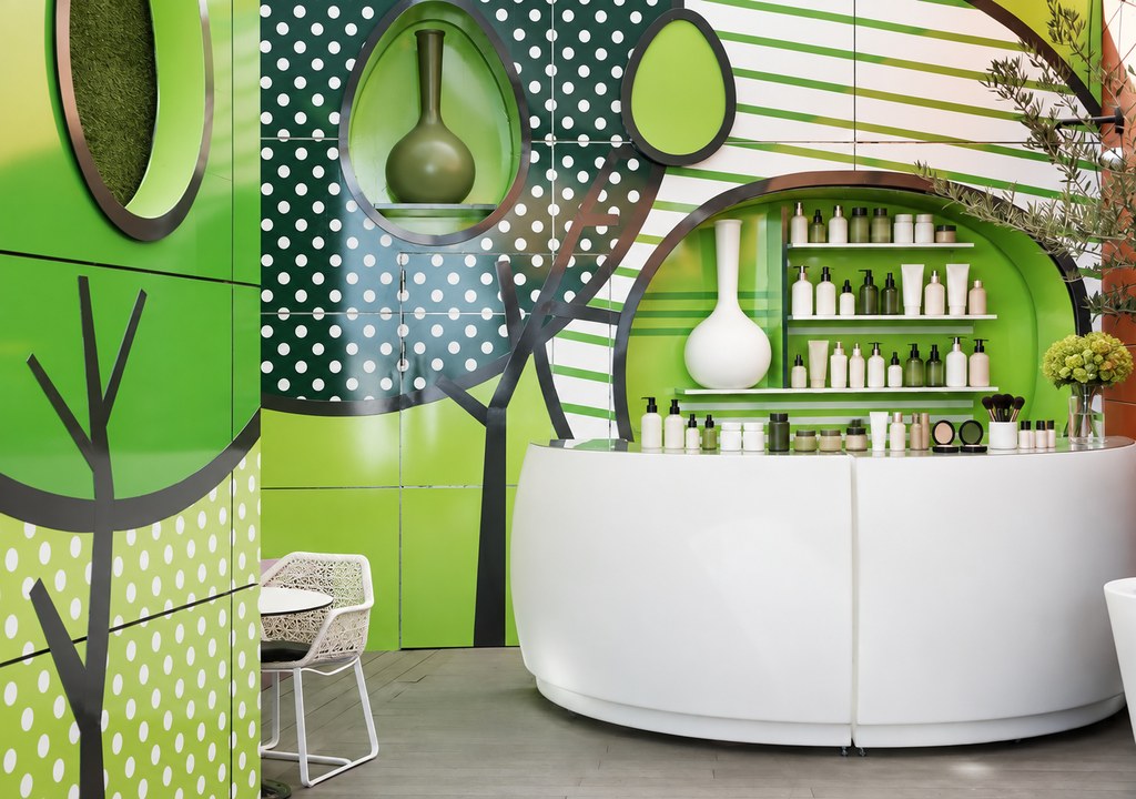Bright, colourful modern hair salon interior with a curved white reception counter and shelves of plain unlabelled colou