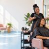 Bright hair salon styling station with a stylist and client seen in a mirror, relaxed unhurried atmosphere