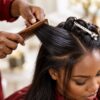Close-up of a stylist's hands braiding or styling a client's hair with a comb, finished look