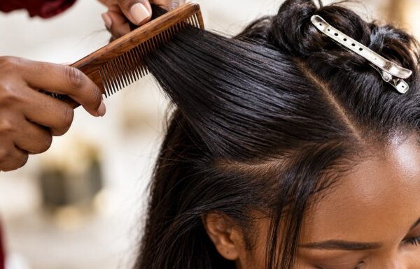Close-up of a stylist's hands braiding or styling a client's hair with a comb, finished look