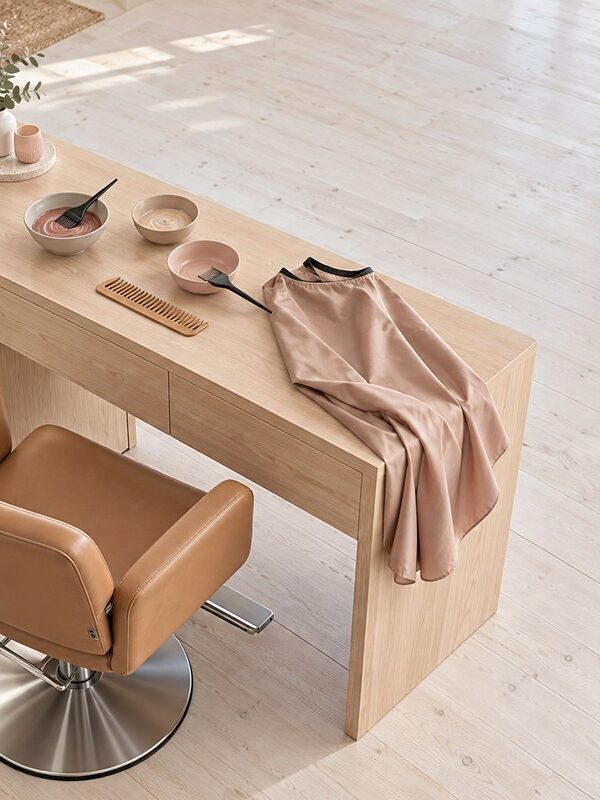 Overhead view of a styled salon hair-colouring station with a wooden shelf and tan leather tool pouch