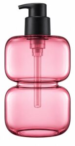 Tall slim rose-pink tinted glass pump bottle of body or face lotion, unlabelled, on white