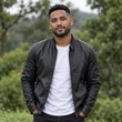 Well-groomed South African man with tidy hair and light beard in a dark leather jacket standing outdoors among greenery