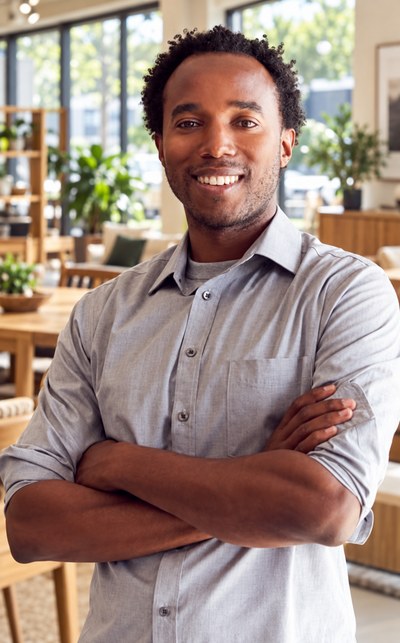 Confident Black South African male lawyer with arms crossed in a grey shirt in a bright office