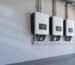 Row of plain white unbranded hybrid inverters mounted on a clean wall in a South African garage